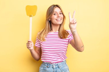 Güzel sarışın kız gülümsüyor ve mutlu görünüyor, zafer ya da barış işareti yapıyor. Öldürme konsepti