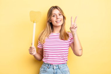 Güzel sarışın kız gülümsüyor ve arkadaş canlısı görünüyor. İki numarayı gösteriyor. Öldürme konsepti