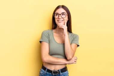 İspanyol güzel kadın mutlu bir şekilde gülümsüyor ve hayal kuruyor ya da şüphe ediyor, yan tarafa bakıyor.