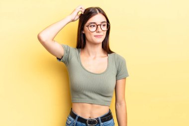 İspanyol güzel kadın şaşkın ve şaşkın hissediyor, başını kaşıyor ve yana bakıyor.