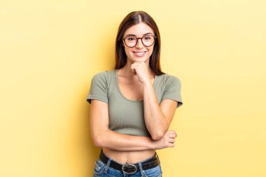 İspanyol güzel kadın mutlu görünüyor ve gülümsüyor, elleri çenesinde, merak ediyor ya da soru soruyor, seçenekleri karşılaştırıyor.