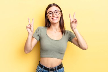 İspanyol güzel kadın gülümsüyor ve mutlu görünüyor, arkadaş canlısı ve tatmin olmuş, zafer ya da barış işareti yapıyor.