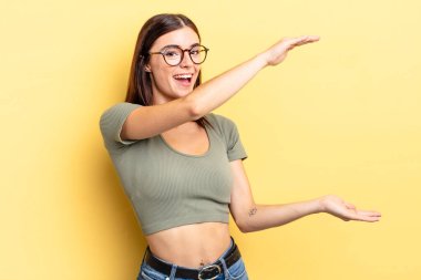 İspanyol güzel kadın gülümsüyor, mutlu, pozitif ve tatmin olmuş hissediyor, fotokopi alanında nesne ya da konsept tutuyor ya da gösteriyor