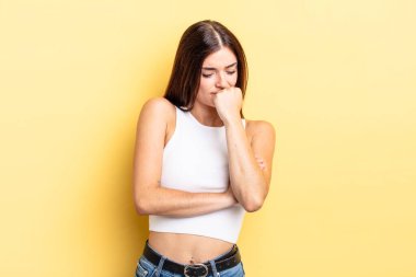 Hispanik güzel kadın ciddi, düşünceli ve endişeli, elleri çenesine bastırılmış şekilde yan bakıyor