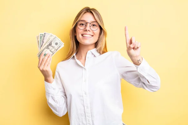 Pretty Blonde Girl Smiling Looking Friendly Showing Number One Dollar — Stock Photo, Image