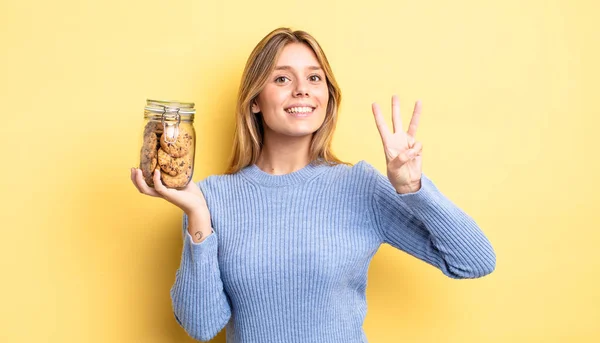 Jolie Fille Blonde Souriante Sympathique Montrant Numéro Trois Concept Cookies — Photo