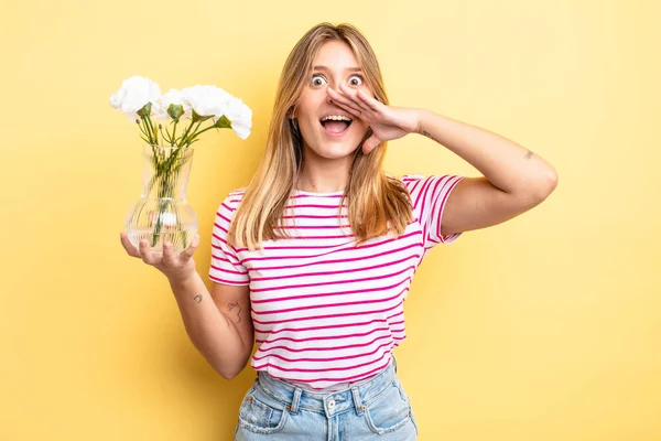 Güzel sarışın kız kendini mutlu hissediyor, elleri ağzının kenarında bağırıyor. Dekoratif çiçek konsepti