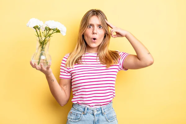 Güzel sarışın kız şaşırmış görünüyor, yeni bir düşünce, fikir ya da konsept fark ediyor. Dekoratif çiçek konsepti
