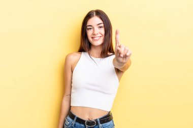 İspanyol güzel kadın gülümsüyor ve arkadaş canlısı görünüyor, bir numarayı gösteriyor ya da ilk eli önde, geri sayıyor.