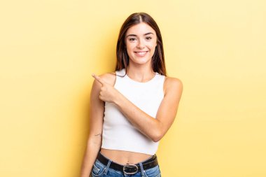 İspanyol güzel kadın neşeyle gülümsüyor, mutlu hissediyor ve yan ve yukarı doğru işaret ediyor, kopya uzayda nesne gösteriyor