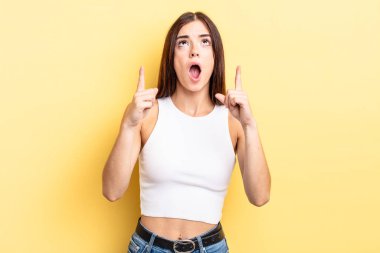 İspanyol güzel kadın şaşırmış, şaşırmış ve ağzı açık görünüyor, iki eliyle boşluğu kopyalamak için yukarı bakıyor.