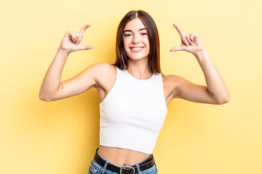 İspanyol asıllı güzel bir kadın iki eliyle kendi gülüşünü çiziyor, olumlu ve mutlu görünüyor, sağIık kavramı.