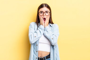 İspanyol güzel kadın şok olmuş ve korkmuş hissediyor, ağzı açık ve elleri yanaklarında korkmuş görünüyor.