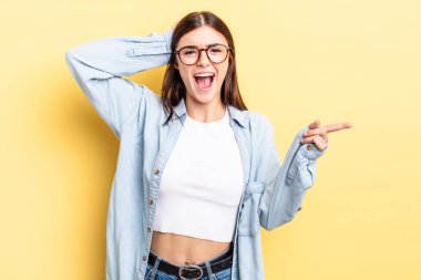 İspanyol güzel bir kadın gülüyor, mutlu, pozitif ve şaşırmış görünüyor, yanal fotokopi alanını işaret eden harika bir fikrin farkına varıyor.