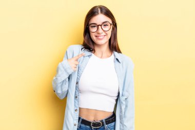 İspanyol güzel kadın gururlu, kendinden emin ve mutlu görünüyor, gülümsüyor ve kendini işaret ediyor ya da bir numara işareti yapıyor.