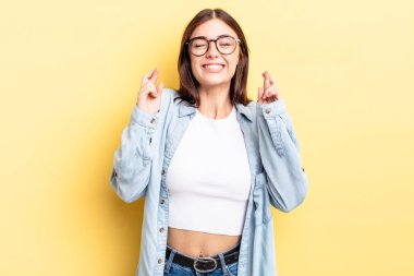 İspanyol güzel kadın gülümsüyor ve endişeyle iki parmağını çapraz yapıyor. Endişeli hissediyor, iyi şanslar diliyor ya da umut ediyor.