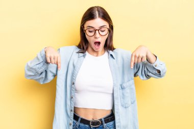 İki eliyle aşağıya bakan ağzı açık, şaşkın, şaşkın ve şaşırmış görünen İspanyol bir kadın.