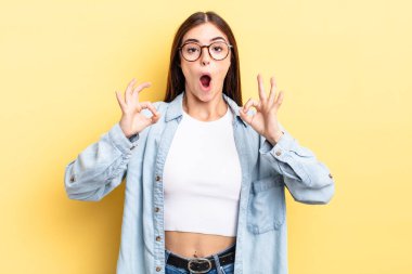 İspanyol güzel kadın şok olmuş, şaşırmış ve şaşırmış hissediyor. Onaylıyor. İki eliyle işaret veriyor.