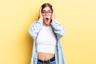 İspanyol güzel kadın hoş olmayan bir şekilde şok olmuş, korkmuş ya da endişeli görünüyor, ağzı sonuna kadar açık ve iki kulağını da elleriyle kapatıyor.