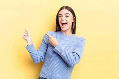 Hispanik güzel kadın neşeli ve şaşırmış hissediyor, şok olmuş bir ifadeyle gülümsüyor ve bir tarafı işaret ediyor.