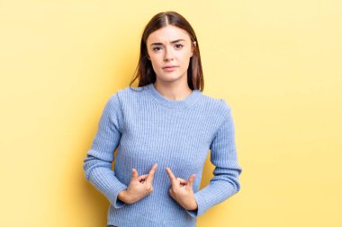 İspanyol asıllı güzel bir kadın, şaşkın ve şaşkın bir bakışla kendini işaret ediyor. Seçildiğine şaşırmış ve şaşırmış.