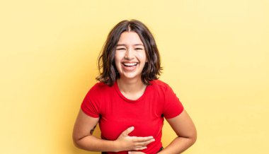 Genç ve güzel bir kız komik bir şakaya yüksek sesle gülüyor, mutlu ve neşeli hissediyor, eğleniyor.