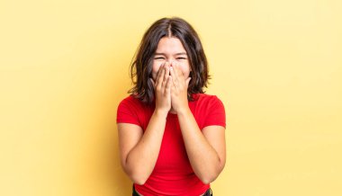 Genç ve güzel kız mutlu, neşeli, şanslı ve şaşkın görünüyor. İki eliyle ağzını kapatıyor.