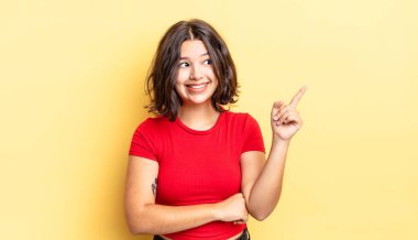 Genç güzel kız mutlu bir şekilde gülümsüyor ve yan bakıyor, merak ediyor, düşünüyor ya da bir fikri var.