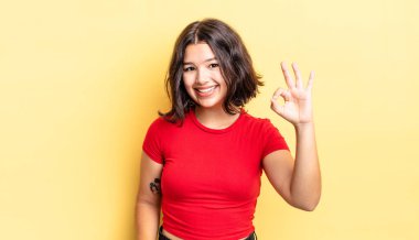 Genç güzel kız mutlu, rahat ve tatmin olmuş hissediyor. Onayını iyi bir hareketle gösteriyor. Gülümsüyor.