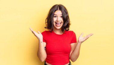 Genç güzel kız mutlu, heyecanlı, şaşırmış ya da şaşırmış hissediyor, gülümsüyor ve hayrete düşüyor.