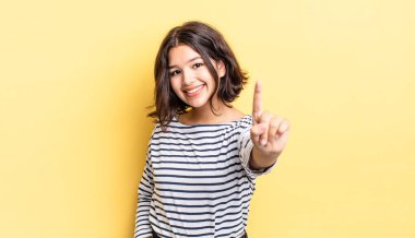 Genç ve güzel bir kız gururla gülümsüyor ve gururla bir numaralı pozu veriyor, kendini lider gibi hissediyor.