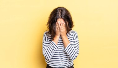 Genç, güzel bir kız üzgün, hayal kırıklığına uğramış, gergin ve depresif, iki eliyle yüzünü kaplayan, ağlayan