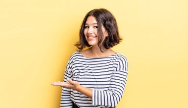 Genç ve güzel bir kız neşeyle gülümsüyor, mutlu hissediyor ve fotokopi alanında bir konsept gösteriyor.