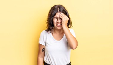 Genç güzel kız uykulu görünüyor, sıkılmış ve esniyor, baş ağrısı ve yüzünün yarısını kaplayan bir elle.