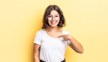 Genç güzel kız mutlu, gururlu ve şaşırmış görünüyor, neşeyle kendini gösteriyor, kendinden emin ve kibirli hissediyor.