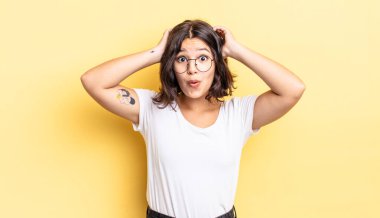 Genç ve güzel bir kız heyecanlı ve şaşırmış görünüyor, ağzı açık, iki eli başının üstünde, kendini şanslı bir kazanan gibi hissediyor.