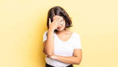 Genç, güzel bir kız stresli, utanmış ya da üzgün görünüyor, baş ağrısı var, yüzü elle kapatılmış.