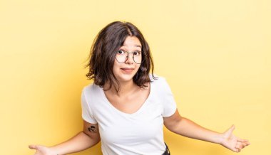 young pretty girl feeling clueless and confused, having no idea, absolutely puzzled with a dumb or foolish look