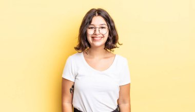 Genç ve güzel kız pozitif ve kendinden emin gülümsüyor. Tatmin olmuş, arkadaş canlısı ve mutlu görünüyor.