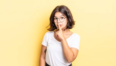 Genç ve güzel bir kız sessizlik ve sessizlik istiyor, parmaklarıyla ağzının önünde işaret ediyor, 