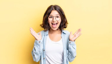 Genç, güzel bir kız mutlu ve heyecanlı görünüyor. Beklenmedik bir sürprizle şoke olmuş. İki eli yüzü açık.