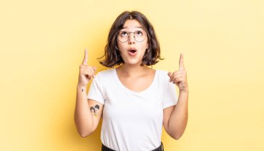 Genç ve güzel bir kız huşu içinde ve ağzı açık. Şok olmuş ve şaşırmış bir bakışla yukarıya bakıyor.