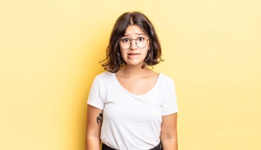 Şaşkın ve kafası karışmış genç bir kız gergin bir hareketle dudağını ısırıyor, sorunun cevabını bilmiyor.