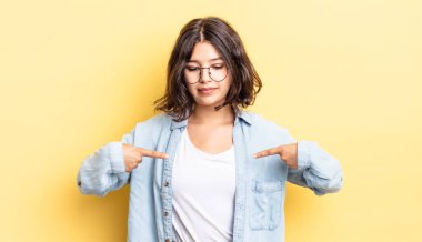 Genç ve güzel bir kız gururlu, pozitif ve iki eliyle göğsünü gösteren