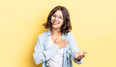 Genç ve güzel bir kız mutlu ve aşık, bir eli kalbinin yanında gülümsüyor ve diğer eli önde uzanıyor.