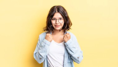 Genç ve güzel bir kız kendinden emin, sinirli, güçlü ve agresif görünüyor. Yumrukları boks pozisyonunda dövüşmeye hazır.