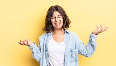 young pretty girl shrugging with a dumb, crazy, confused, puzzled expression, feeling annoyed and clueless