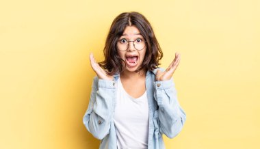 Genç ve güzel bir kız beklenmedik bir sürpriz yüzünden şaşkın, heyecanlı, gülen, şaşkın ve mutlu hissediyor.