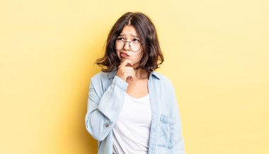 Genç güzel kız düşünüyor, kuşkulu ve şaşkın hissediyor, farklı seçeneklerle, hangi kararı vereceğini merak ediyor.