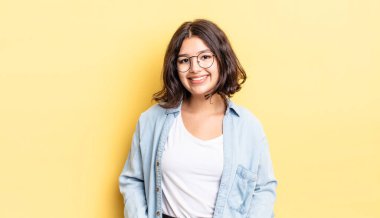 Genç ve güzel bir kız neşeli bir şekilde gülümsüyor. Olumlu, mutlu, kendinden emin ve rahat bir ifadeyle.